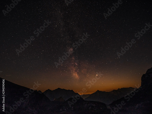 Golden evening light gently illuminates the mountains under the starry sky.