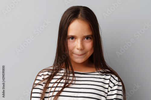 Little girl making a grimace over a grey background