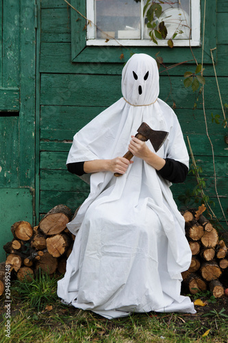 White Ghost with axe in an autumn garden for Halloween party. Halloween Concept. Halloween holiday
