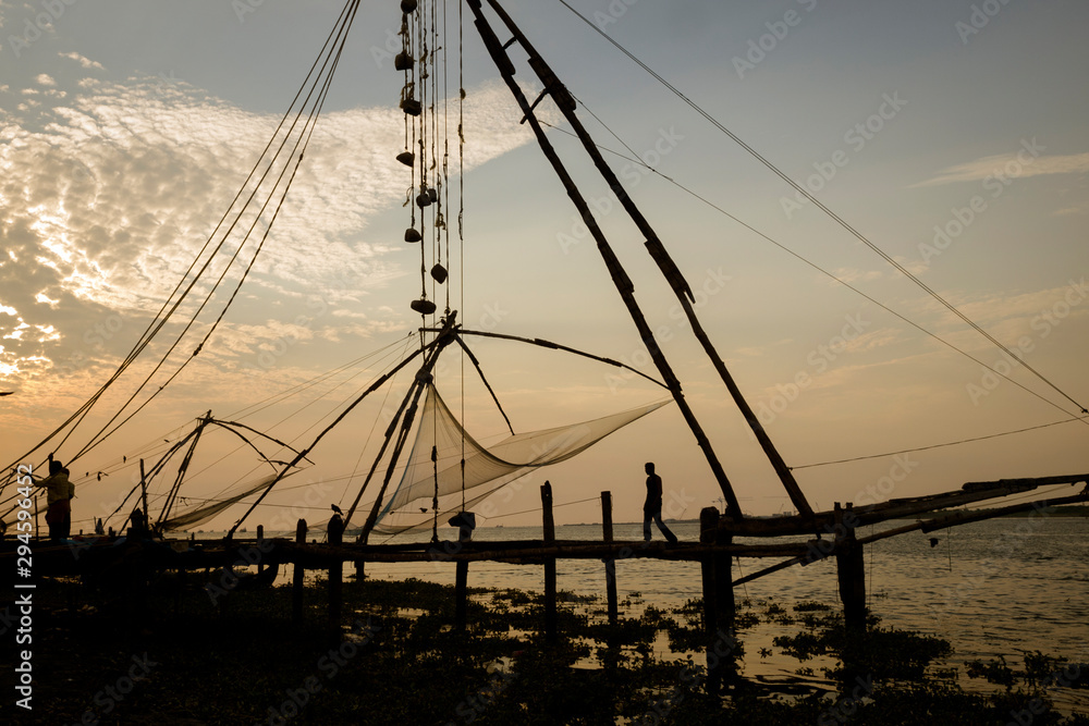 Fishermen working at the chinese fishing nets at evening, Kochi, Kerala, India