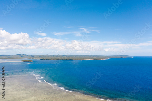 Fototapeta Naklejka Na Ścianę i Meble -  Seascape, coast of the island of Siargao, Philippines. Blue sea with waves and sky with big clouds, top view.