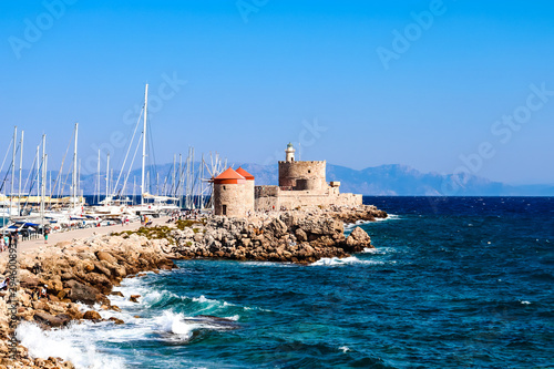 The symbol of Rhodes is a windmill and the fort of St. Nicholas in the port of Mandraki with a view of the harbor