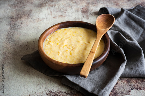 фотографія Corn porridge in wooden bowl with wooden spoon in vintage style on grey backgrou