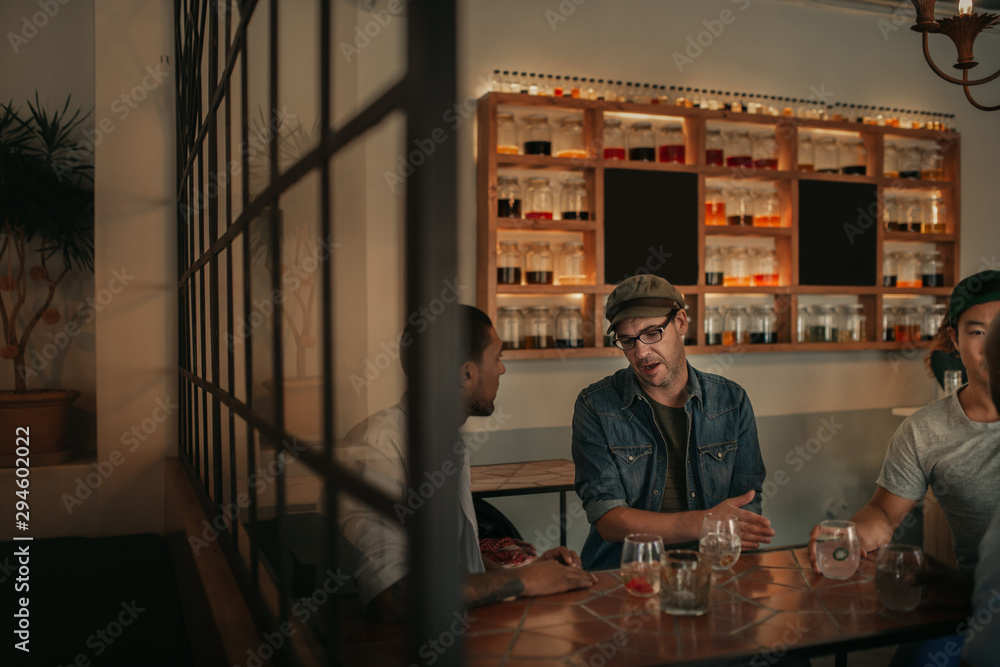 Friends talking together over drinks in a bar at night Friends talking together over drinks in a bar at night