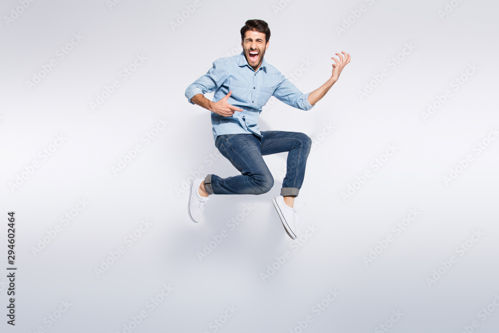Full length photo of wild multiethnic guy jumping high at hard rock concert playing imagine electric guitar wear casual denim clothes isolated white color background Full length photo of wild multiethnic guy jumping high at hard rock concert playing imagine electric guitar wear casual denim clothes isolated white color background