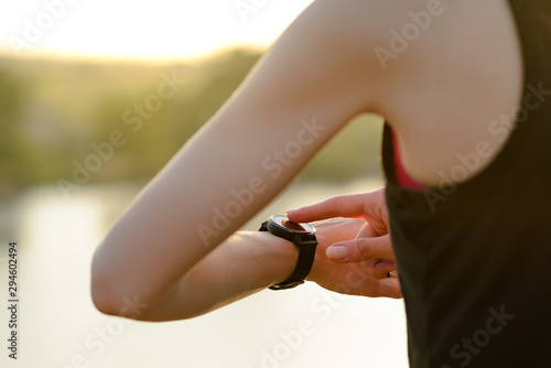 Woman Runner Resting on the Trail at Sunset and Using Smartwatch. Closeup of Hands with Smart Watch. Sports Concept.