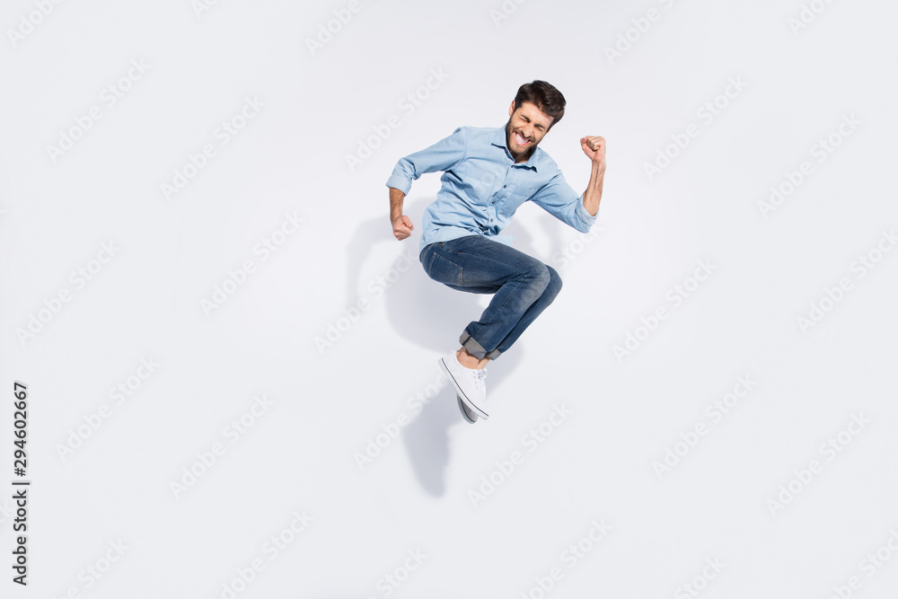 Full body profile photo of funny arabian guy jumping high rejoicing of great win raising fists wear casual denim shirt isolated white color background