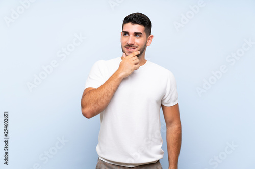 Caucasian handsome man over isolated blue background looking to the side