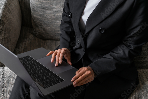 Close up of unrecognizable young woman in business suit using laptop touchpad while sitting in armchair. Concept of internet for business and entertainment © VideoFlow