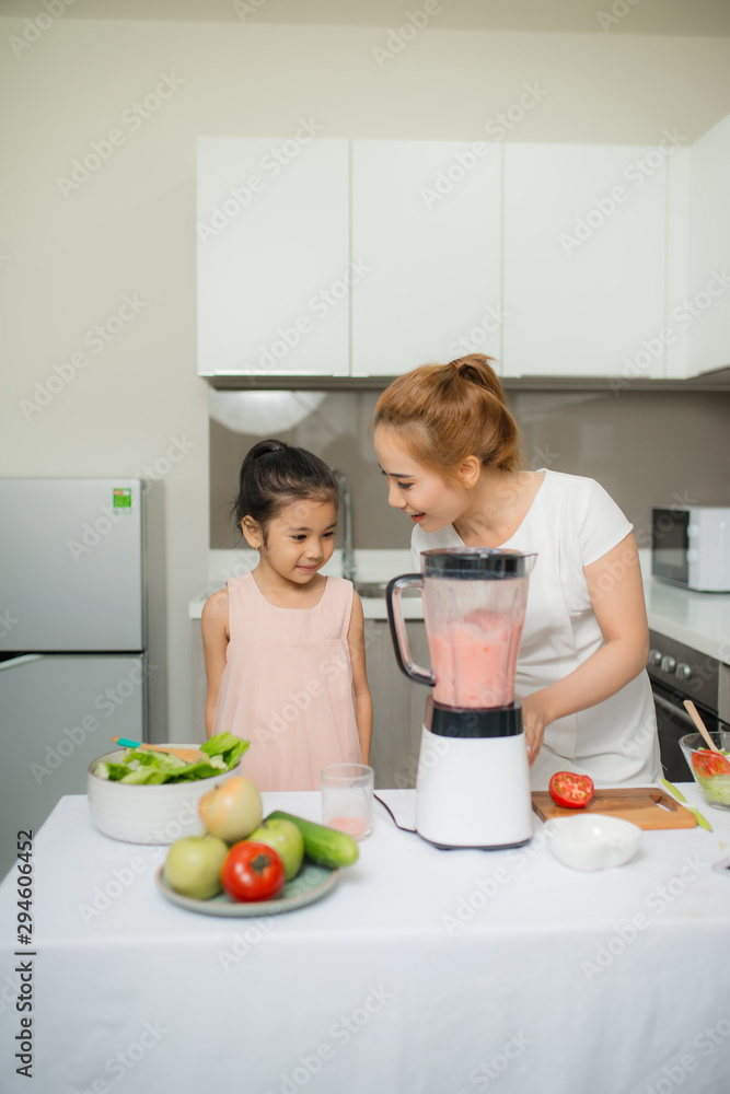 Mother assisting daughter to prepare juice in kitchen at home Mother assisting daughter to prepare juice in kitchen at home