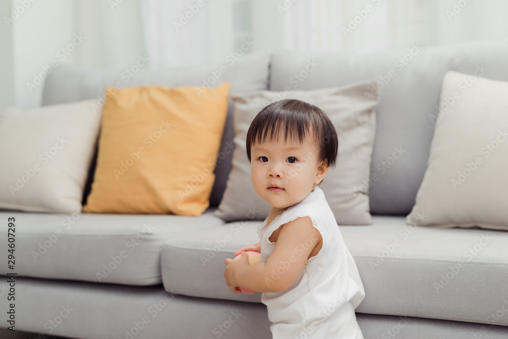 Cute little baby girl standing next to sofa at living room Cute little baby girl standing next to sofa at living room