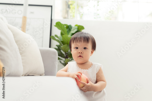 Lovely standing baby next to the sofa. Cute portrait of happy face baby girl