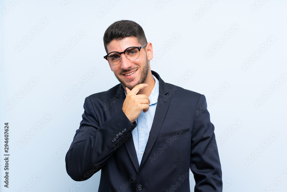 Handsome man over isolated blue background with glasses and smiling Handsome man over isolated blue background with glasses and smiling
