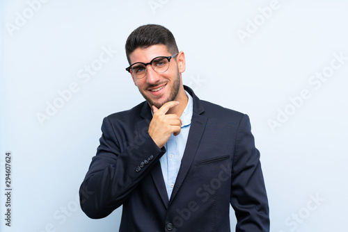 Handsome man over isolated blue background with glasses and smiling