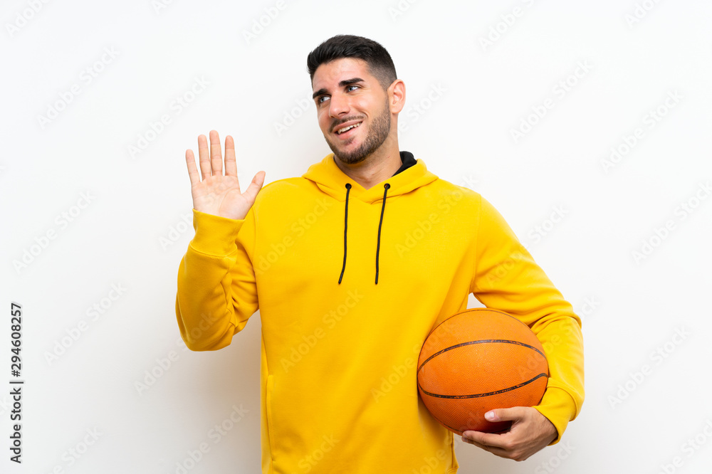 Handsome young basketball player man over isolated white wall saluting with hand with happy expression Handsome young basketball player man over isolated white wall saluting with hand with happy expression