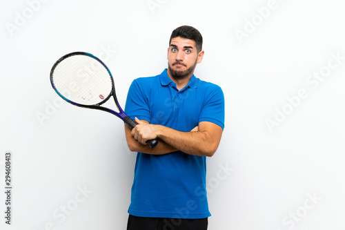 Handsome young tennis player man over isolated white wall making doubts gesture while lifting the shoulders © luismolinero