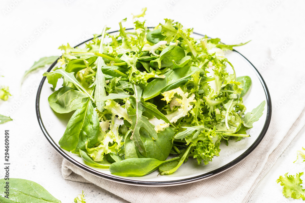 Green salad leaves mix on white table. Green salad leaves mix on white table.