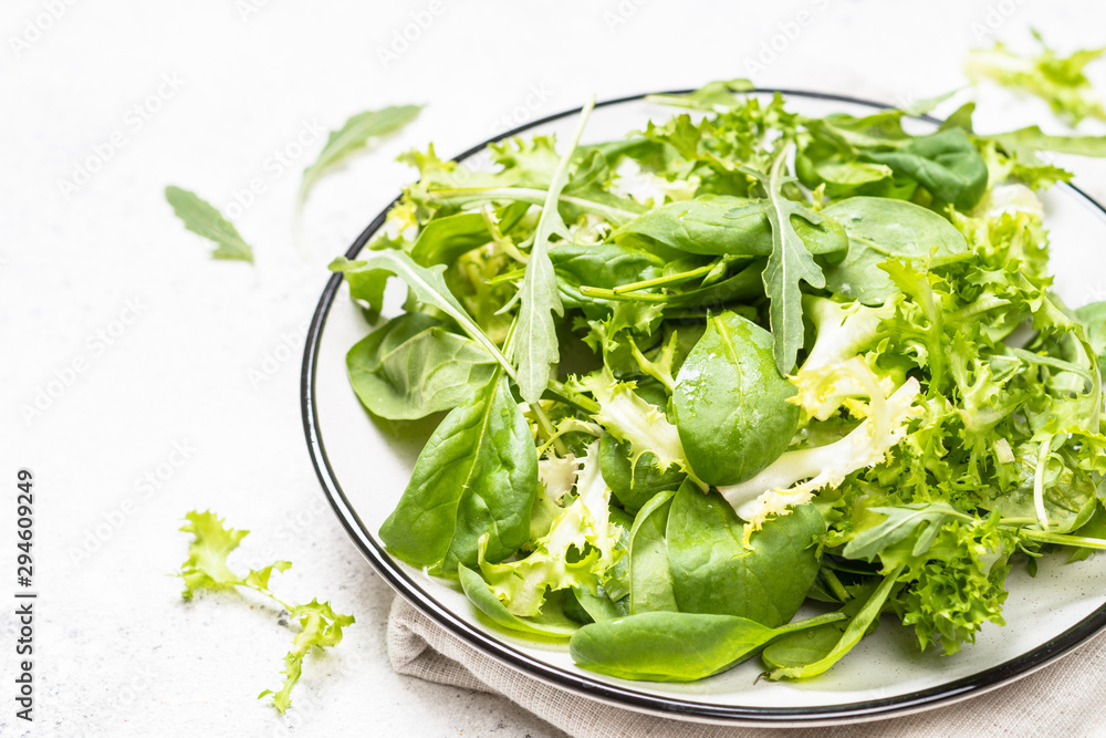 Green salad leaves mix on white table. Green salad leaves mix on white table.