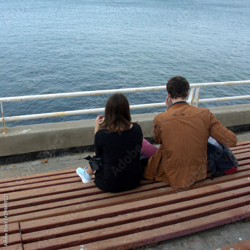 guy and girl are resting on the sea promenade
