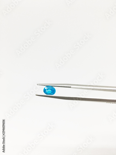 Holding a blue sapphire with stainless steel tweezers isolated on white background.