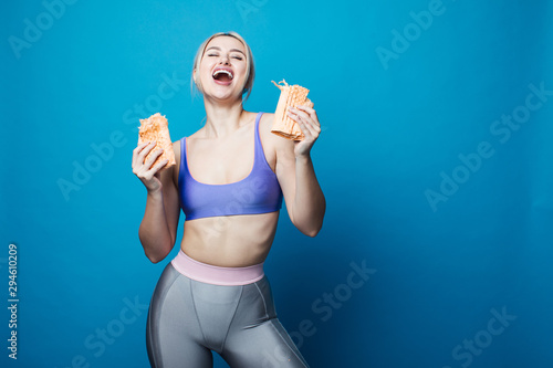 Close up of hungry girl with opened mouth, holding and eating big hamburger. Pretty woman with beautiful hairstyle and red lips. Concept of fast food. © Сергей Уланов