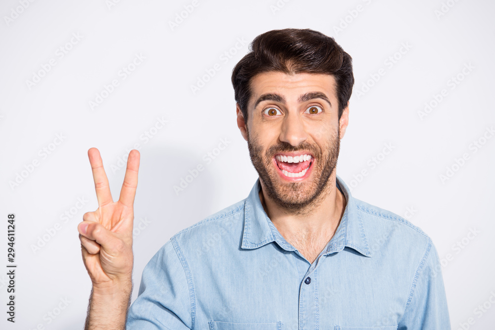 Close up photo of amazing handsome guy showing v-sign symbol greets friends in good mood wear casual denim shirt isolated white color background Close up photo of amazing handsome guy showing v-sign symbol greets friends in good mood wear casual denim shirt isolated white color background