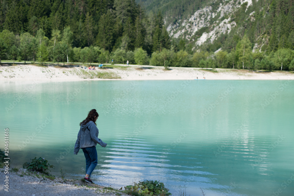 A girl walks by the turquoise lake