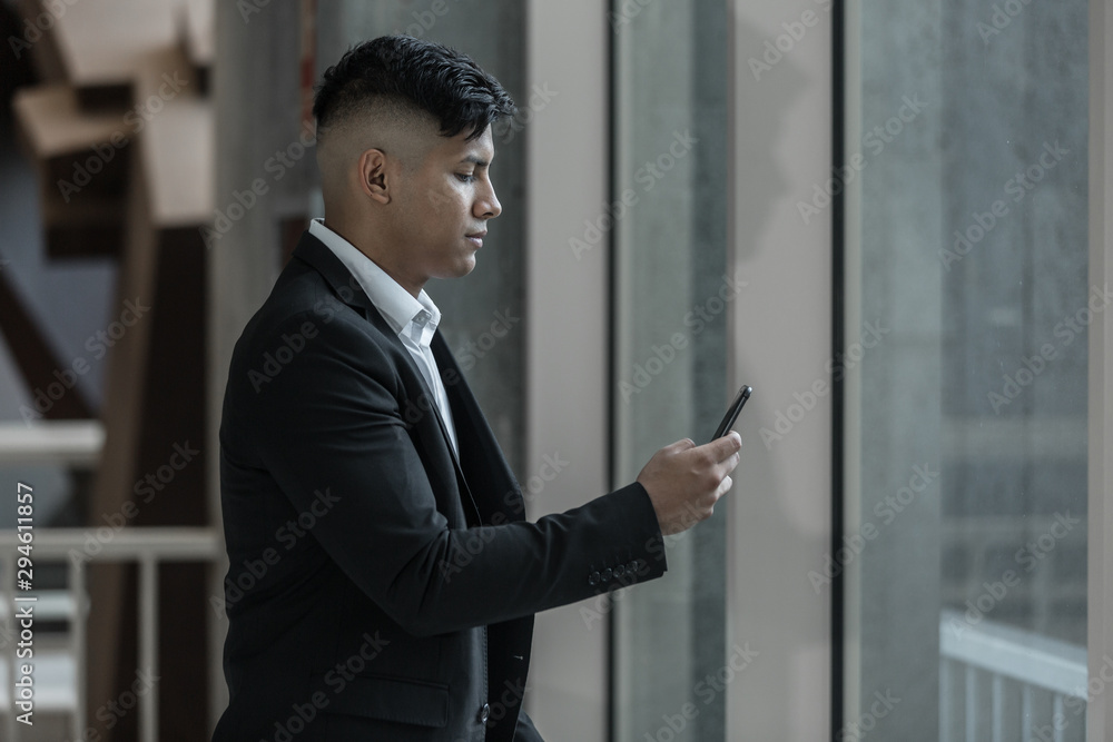 Ethnic businessman using smartphone near window Ethnic businessman using smartphone near window
