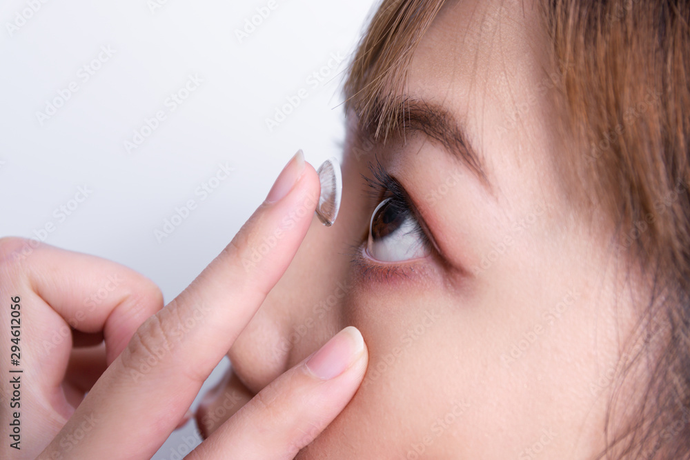 Closeup young woman putting contact lens in her eye. Closeup young woman putting contact lens in her eye.
