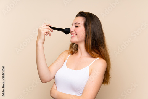 Young brunette girl with makeup brush over isolated background