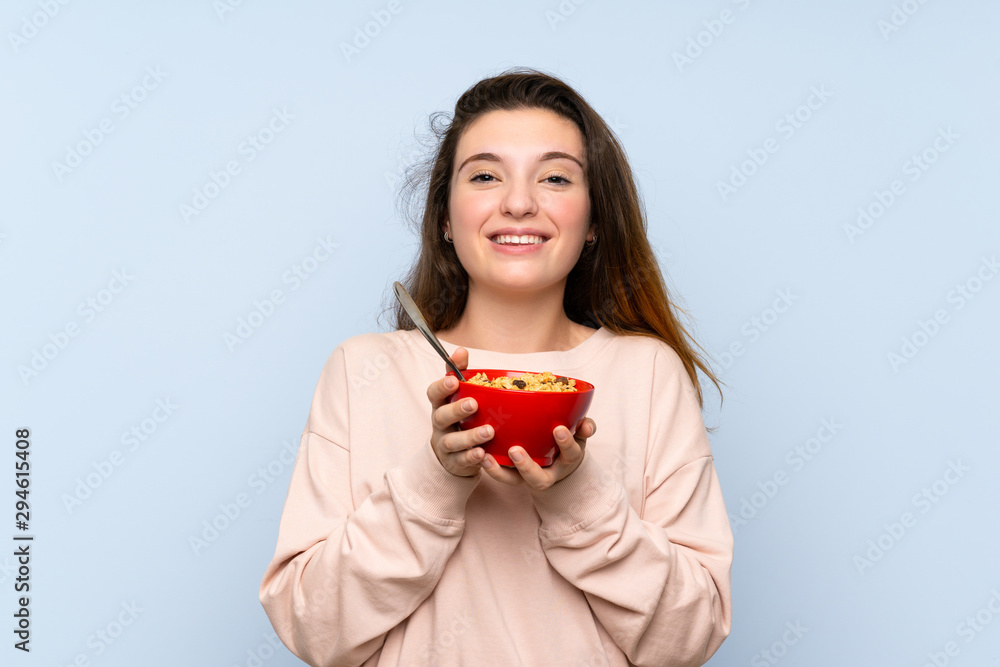 Young brunette girl over isolated blue background holding a bowl of cereals Young brunette girl over isolated blue background holding a bowl of cereals