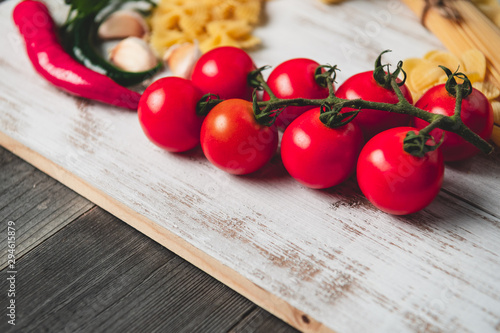 Tasty appetizing italian spaghetti pasta ingredients for kitchen cuisine with tomato, cheese parmesan, olive oil, fettuccine and basil on wooden brown table. Food Italian recipe homemade. Top view