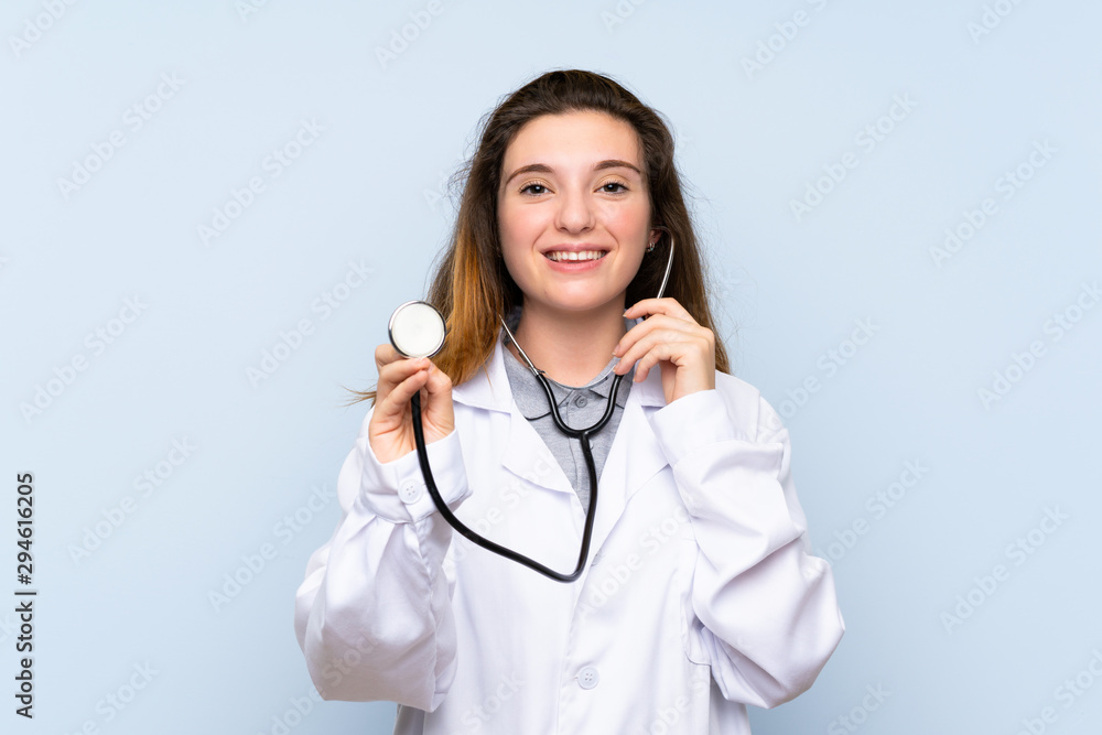 Young brunette girl over isolated blue background with doctor gown Young brunette girl over isolated blue background with doctor gown