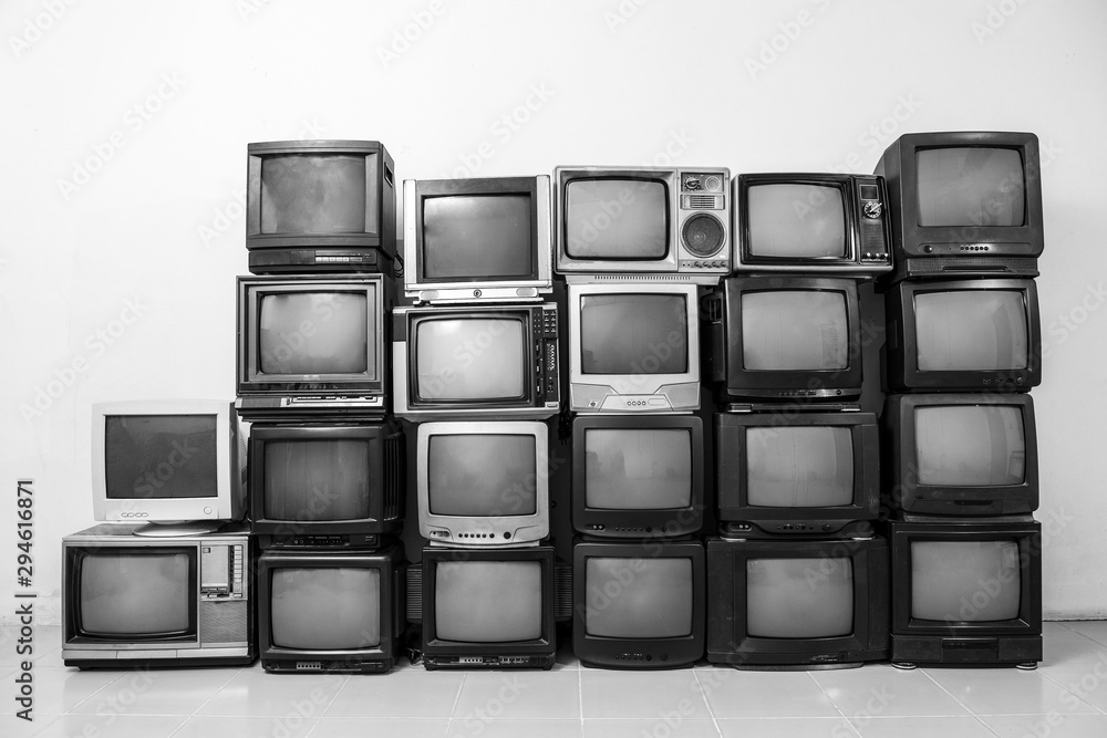 White and black, many retro old TVs piled together on the floor in the room. Television wall White and black, many retro old TVs piled together on the floor in the room. Television wall