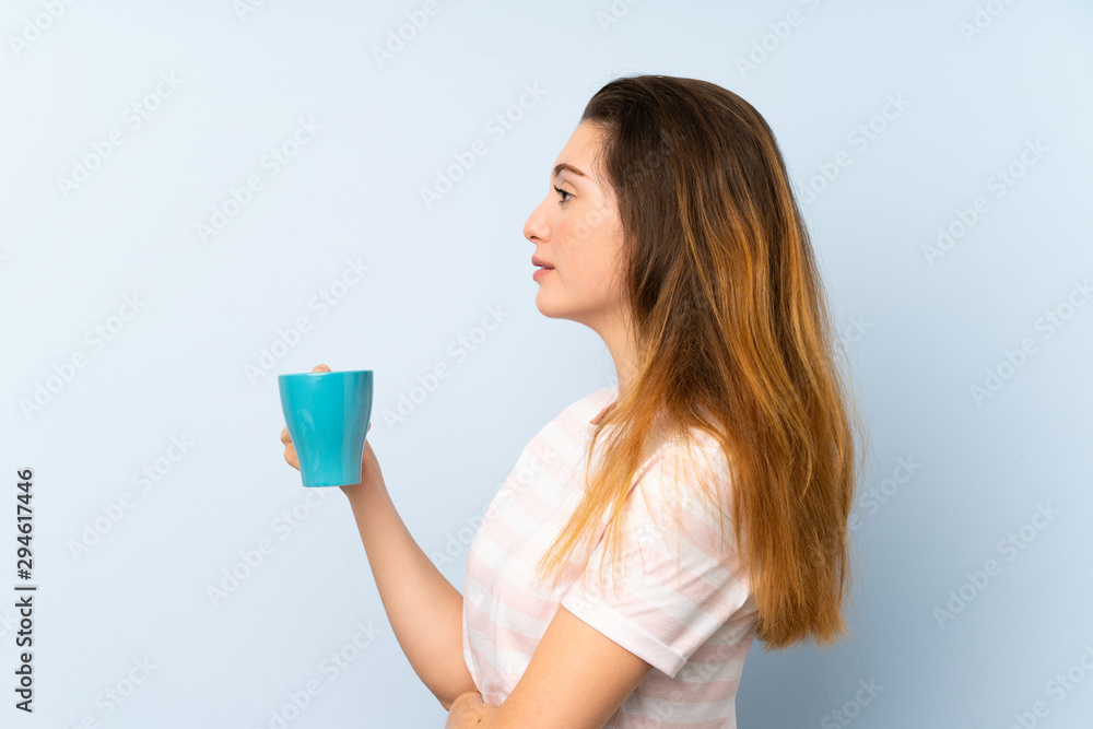 Young brunette girl holding a cup of coffee over isolated background Young brunette girl holding a cup of coffee over isolated background