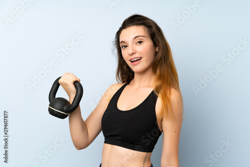 Young brunette girl making weightlifting with kettlebell over isolated background