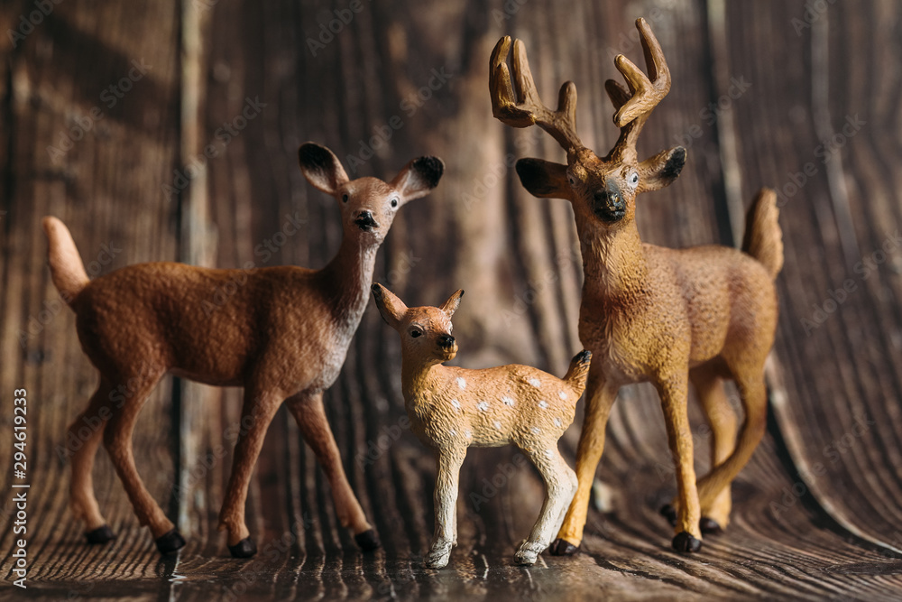 figure of a toy deer, DOE and fawn on a wooden background