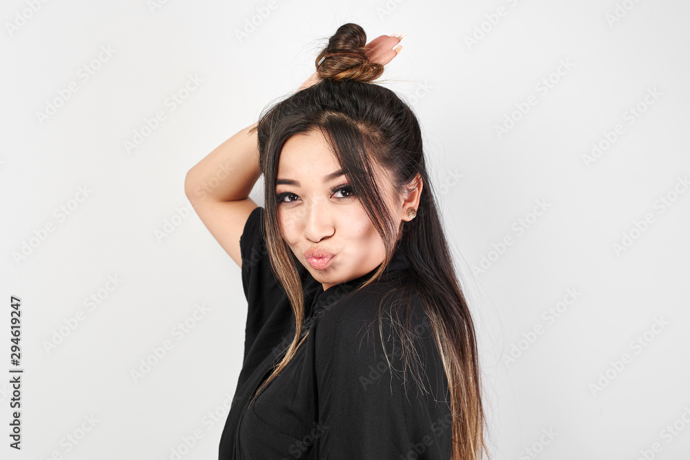 Pretty Kazakh Asian young woman in black with trendy bun of hair on head smiles and poses with stylish hairstyle isolated in white studio Pretty Kazakh Asian young woman in black with trendy bun of hair on head smiles and poses with stylish hairstyle isolated in white studio