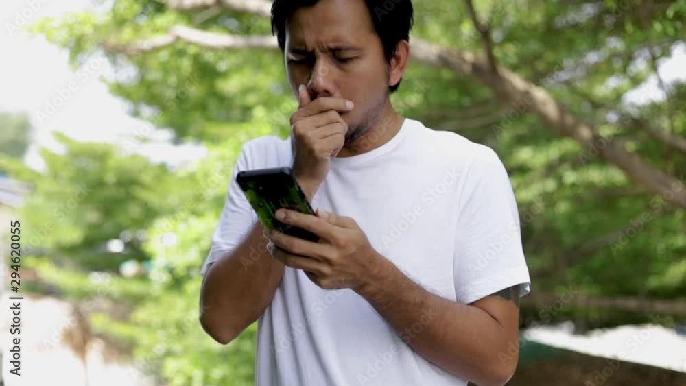 Young Asian Man coughing and covering mouth and using smartphone, take care of your Health concept, Health care concept Young Asian Man coughing and covering mouth and using smartphone, take care of your Health concept, Health care concept