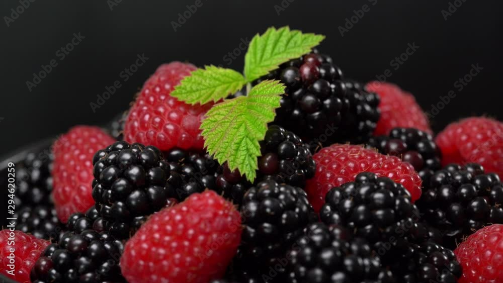 Background from fresh organic blackberries and raspberries. Lot of ripe juicy wild fruit raw berries on a plate rotates. Blackberry and raspberry, close up Background from fresh organic blackberries and raspberries. Lot of ripe juicy wild fruit raw berries on a plate rotates. Blackberry and raspberry, close up