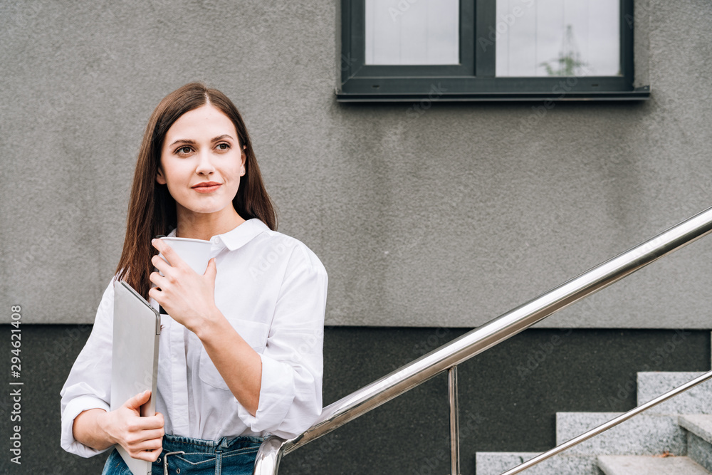 attractive young woman in white shirt holding laptop on street attractive young woman in white shirt holding laptop on street