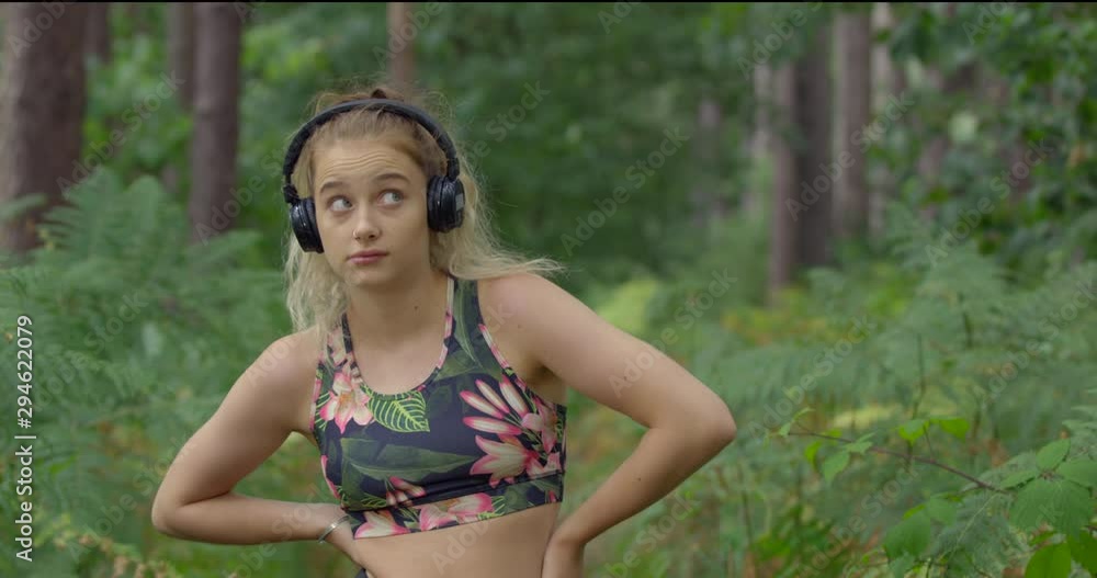 Portrait of Pretty Blonde Young Fitness Woman in Nature Forest. Cute Girl in Headphones and Gym Sports Top. Expressive Funny Workout Lady. British Wood on Summers Day. Portrait of Pretty Blonde Young Fitness Woman in Nature Forest. Cute Girl in Headphones and Gym Sports Top. Expressive Funny Workout Lady. British Wood on Summers Day.