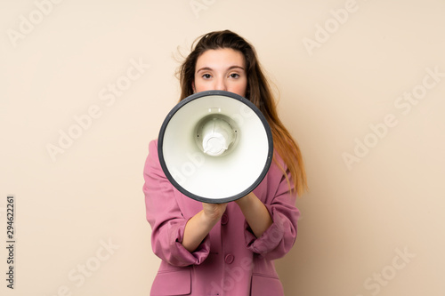 Young brunette girl with blazer over isolated background shouting through a megaphone