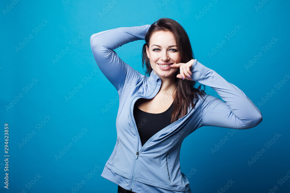 Portrait of an excited attractive young woman dressed bodysuit. Young athletic and beautiful girl. Blue background Portrait of an excited attractive young woman dressed bodysuit. Young athletic and beautiful girl. Blue background