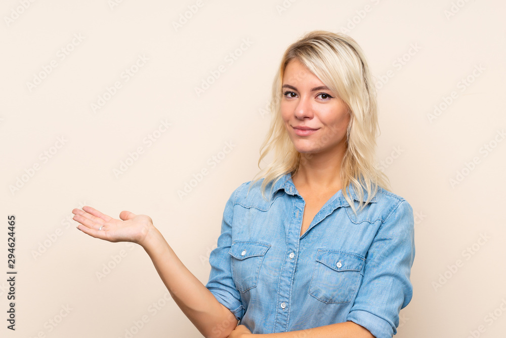 Young blonde woman over isolated background holding copyspace imaginary on the palm Young blonde woman over isolated background holding copyspace imaginary on the palm
