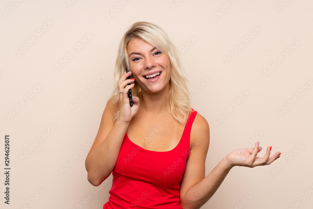 Young blonde woman over isolated background keeping a conversation with the mobile phone with someone Young blonde woman over isolated background keeping a conversation with the mobile phone with someone