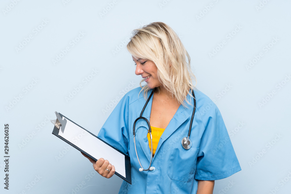 Young blonde woman over isolated background with doctor gown and holding a folder Young blonde woman over isolated background with doctor gown and holding a folder