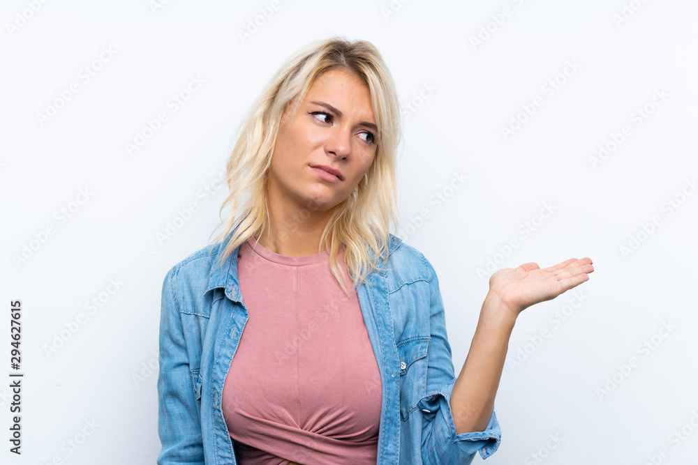 Young blonde woman over isolated white background holding copyspace with doubts Young blonde woman over isolated white background holding copyspace with doubts