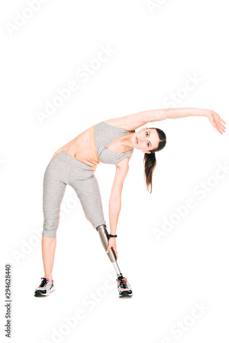 full length view of disabled sportswoman with prosthesis stretching isolated on white