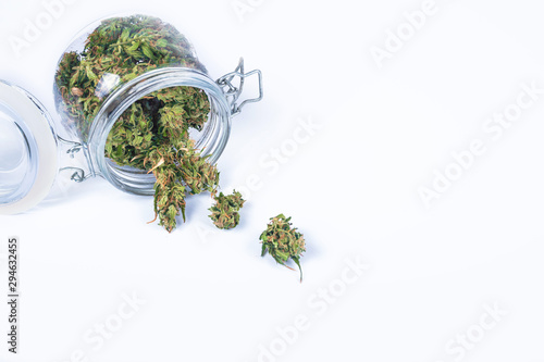 Fresh green buds or flowers of cannabis marijuana weed in opened glass jar isolated on white background. Alternative treatment. Medical cannabis. Copy space.